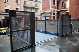  Mesa de muelle de carga con barandilla de seguridad en posición alta, portón de acceso con cerradura electromecánica abierto.